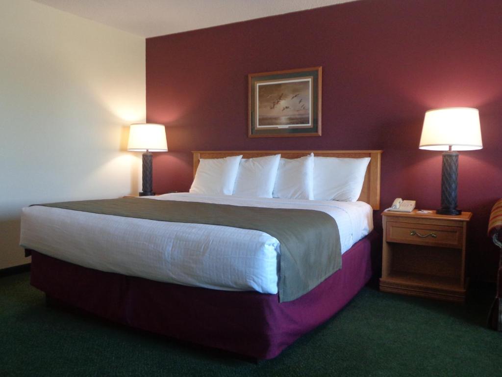 a large bed in a hotel room with two lamps at AmericInn by Wyndham Madison SD in Madison