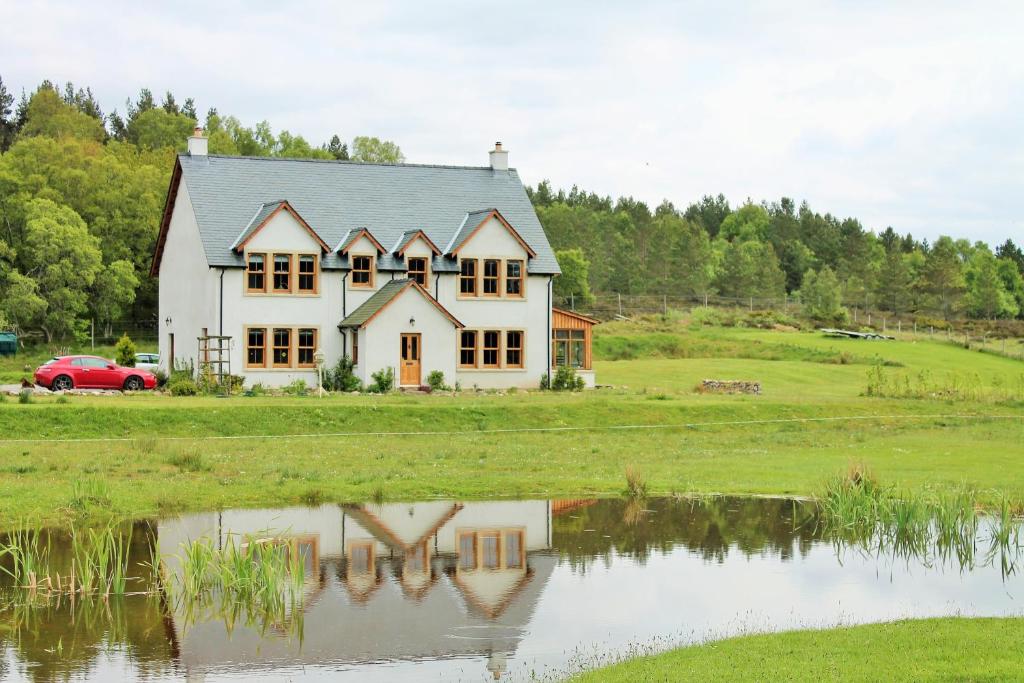 a white house with a reflection in a pond at Ach-Na-Sidhe in Dores