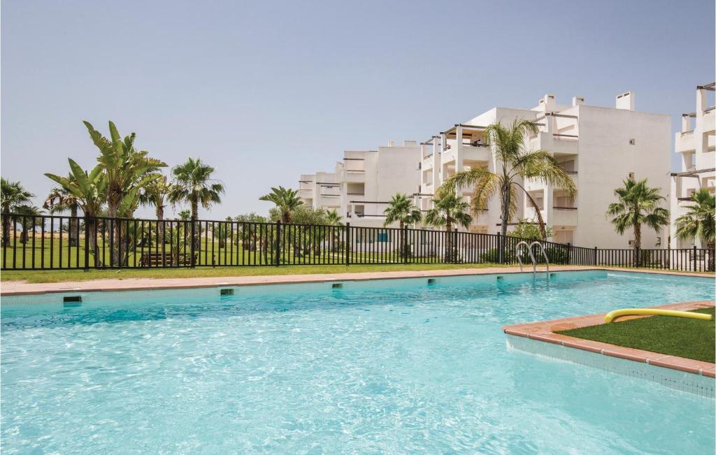 a swimming pool in front of a building with palm trees at 2 Bedroom Cozy Apartment In Roldn in Roldán