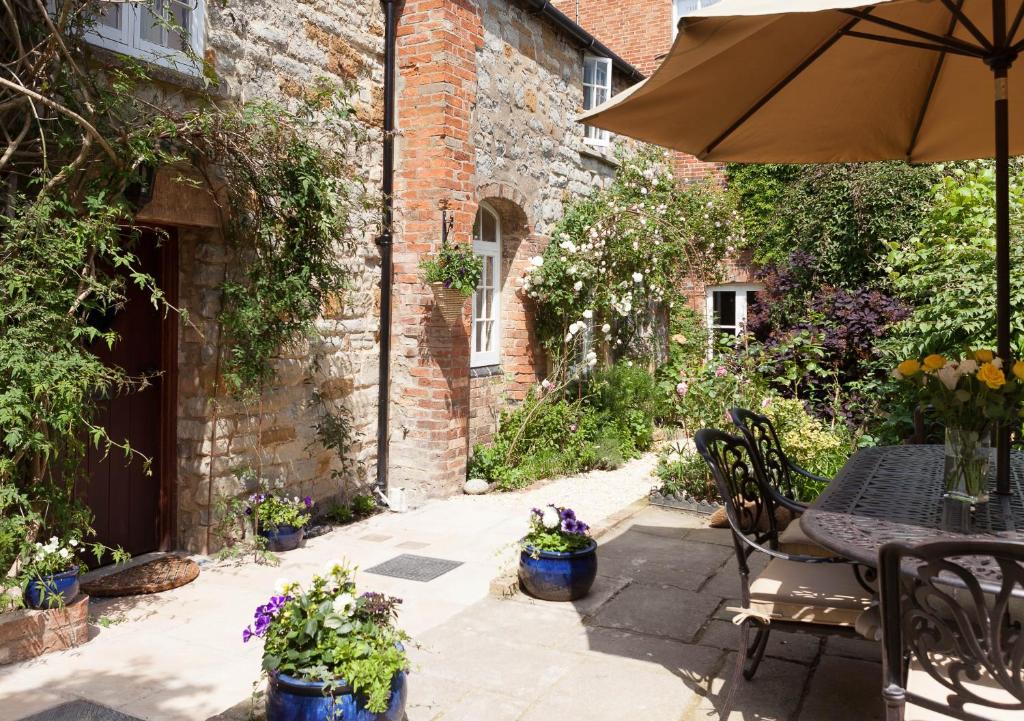 a patio with an umbrella and a table and chairs at The Old Kiln House in Shipston on Stour