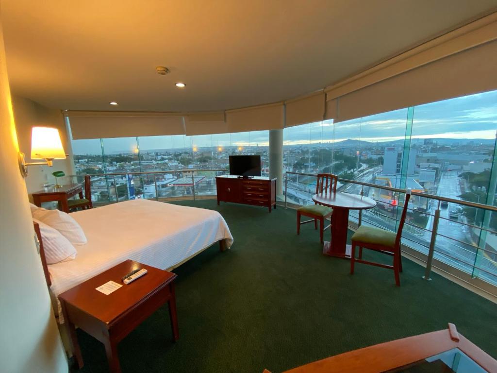 a hotel room with a bed and a balcony with a view at Hotel Enterprise Inn Poliforum in León