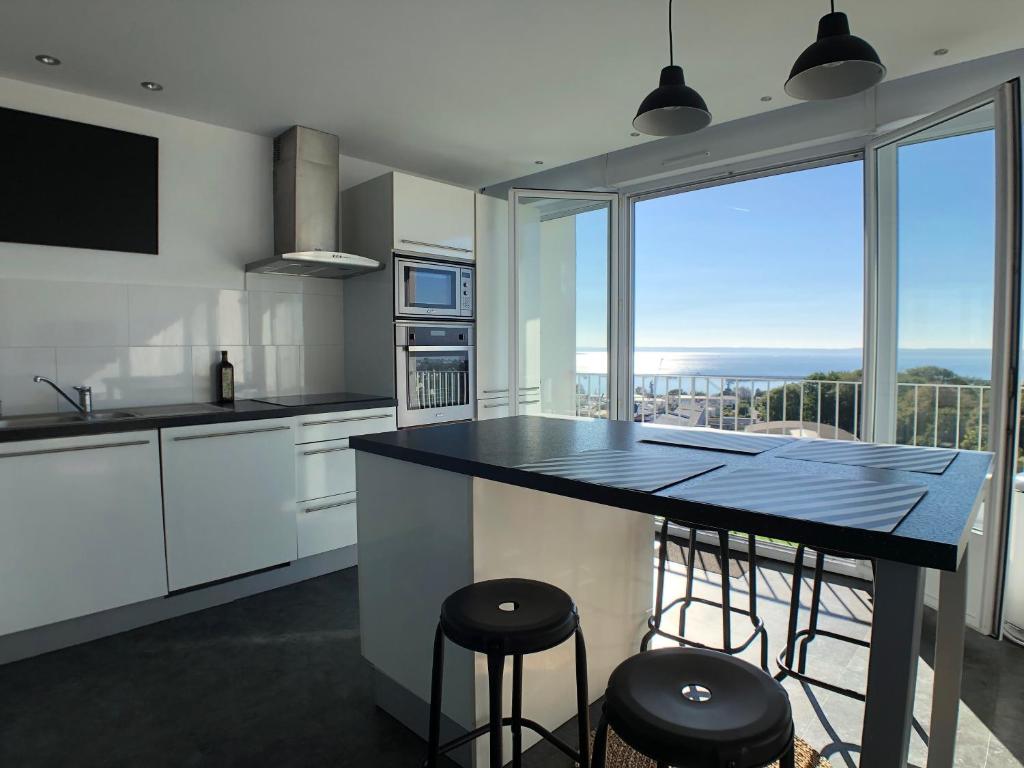 a kitchen with a large window and a counter with stools at Superbe appartement avec une vue mer panoramique in Brest