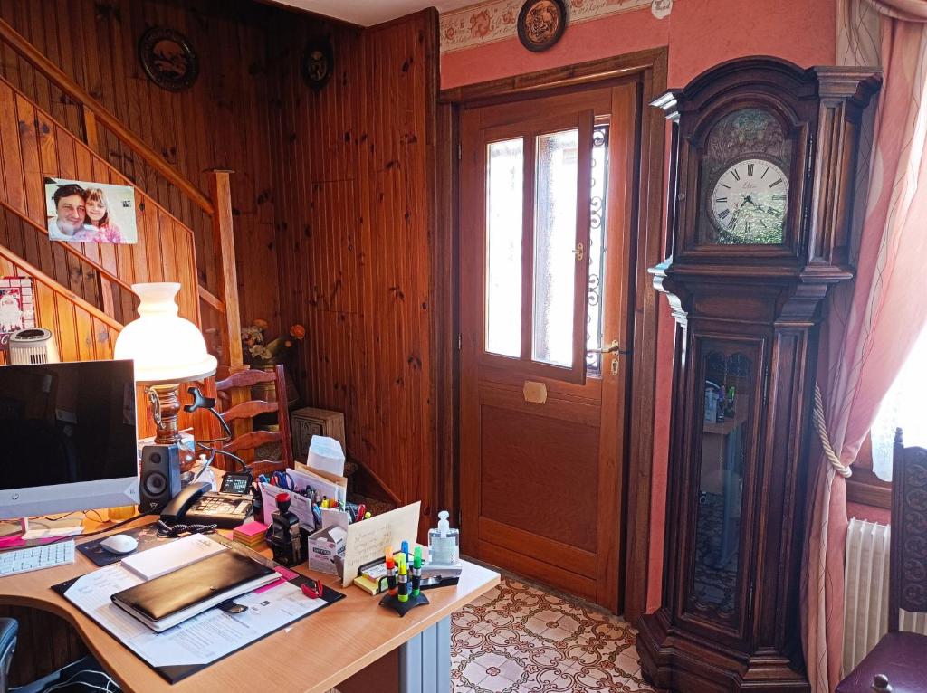 una oficina con escritorio y reloj de abuelo en Chambre d'hôte, en Allouagne