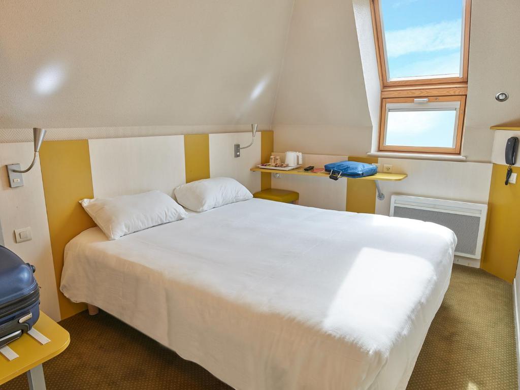 Un dormitorio con una gran cama blanca y una ventana en Hôtel REVOTEL Nancy Centre Gare et Congrès en Nancy