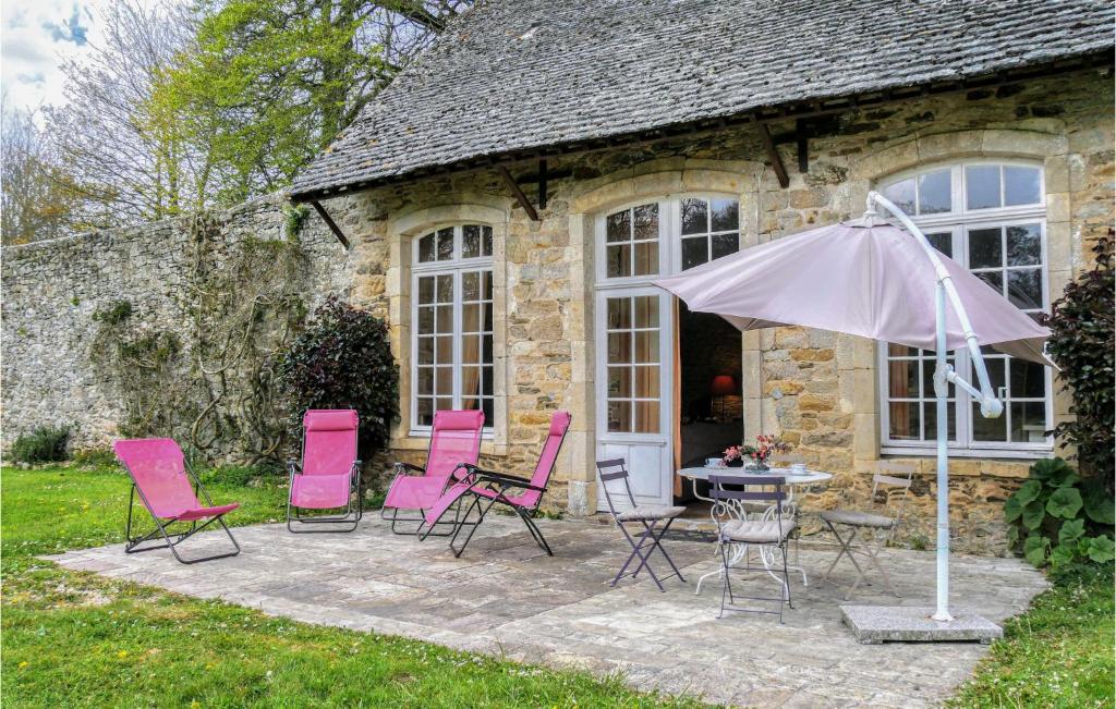 un groupe de chaises et un parasol devant un bâtiment dans l'établissement 3 Bedroom Lovely Home In Gonneville-le-theil, à Gonneville