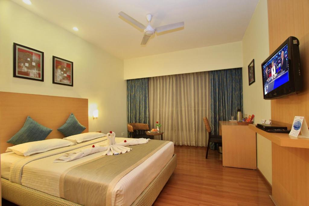 a hotel room with a bed and a flat screen tv at La Sara Hometel in Bangalore
