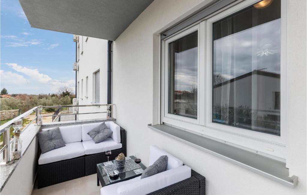 Elle comprend un balcon doté d'un mobilier blanc et de grandes fenêtres. dans l'établissement 1 Bedroom Amazing Apartment In Peroj, à Peroj