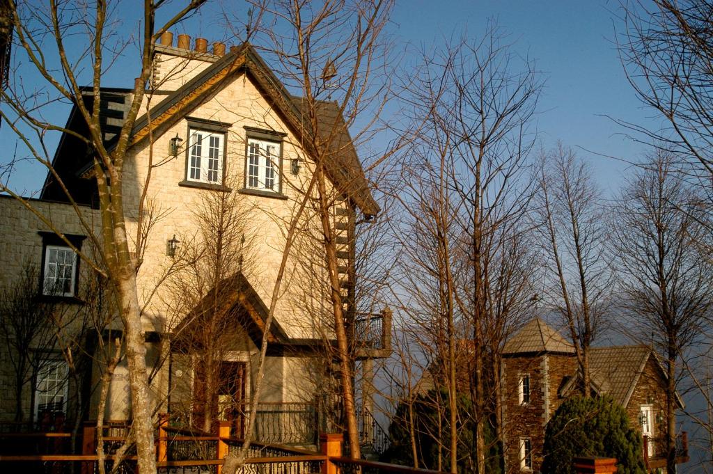 Una casa vieja con un árbol delante. en Shangrila Music Villa, en Renai