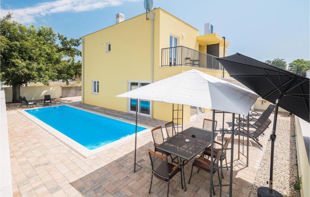 eine Terrasse mit einem Tisch, einem Sonnenschirm und einem Pool in der Unterkunft Cozy Home In Porec With Kitchen in Poreč
