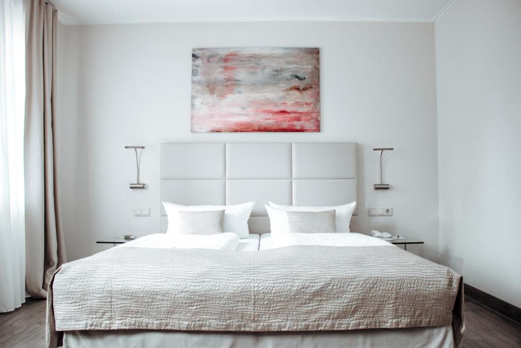 a white bedroom with a large bed with white sheets at Clostermanns Hof in Niederkassel