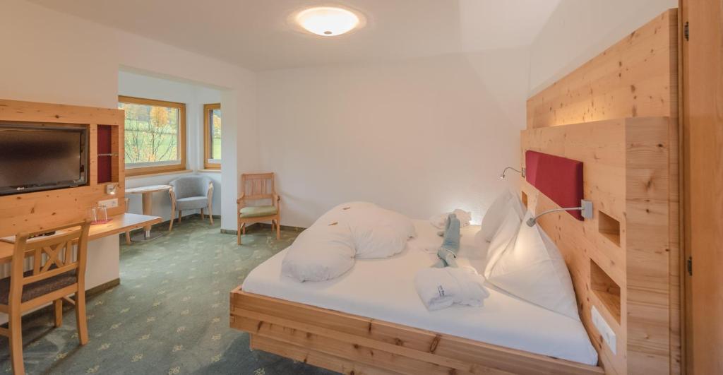 una stanza con un letto, una scrivania e una televisione di Hotel Berghof a Ramsau am Dachstein