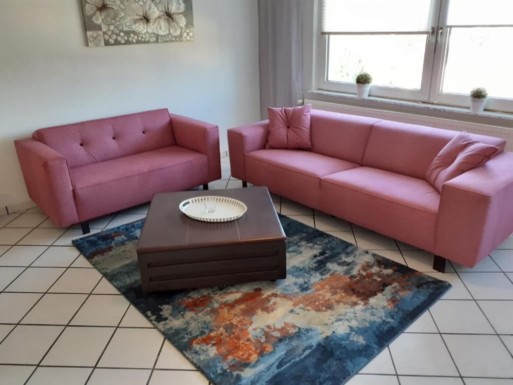 Sala de estar con 2 sofás rosados y mesa de centro en Apartment 31K en Castrop-Rauxel