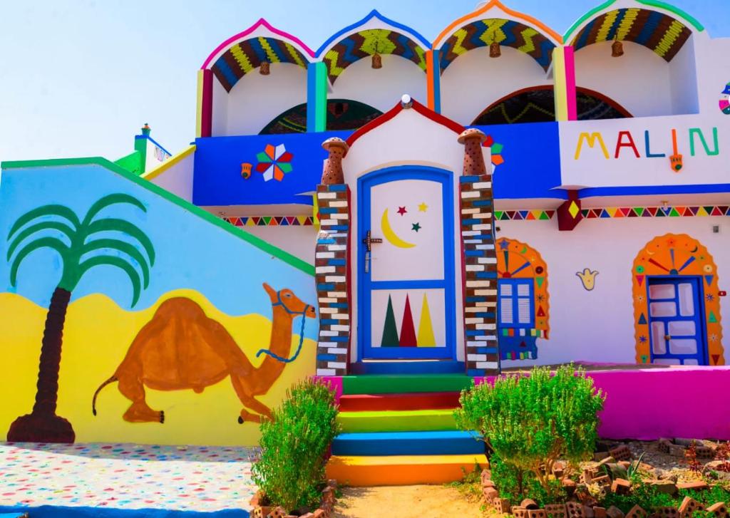 ein farbenfrohes Gebäude mit einem darauf gemalten Kamel in der Unterkunft malindy KA ماليندى كا in Assuan