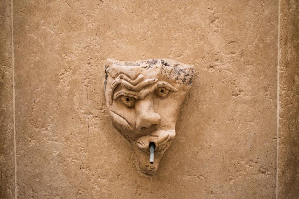 a statue of a face with a cigarette in its mouth at Le Cacinare in Modica