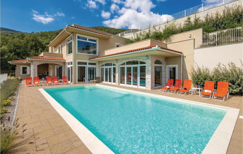 a house with a swimming pool and orange chairs at Awesome Home In Veprinac With 5 Bedrooms, Sauna And Outdoor Swimming Pool in Veprinac