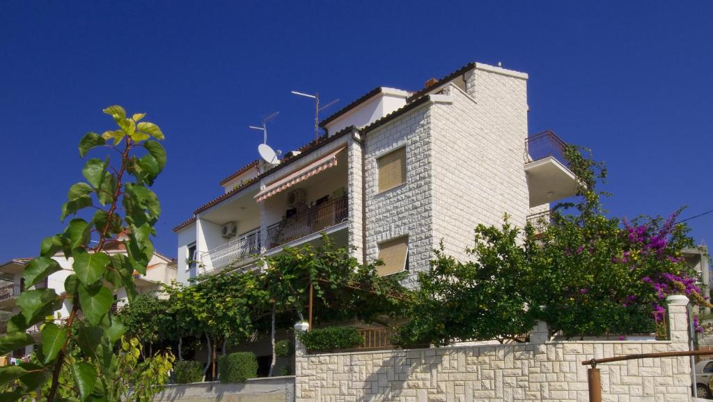 a white brick building with trees in front of it at Apartments Jurić in Podstrana