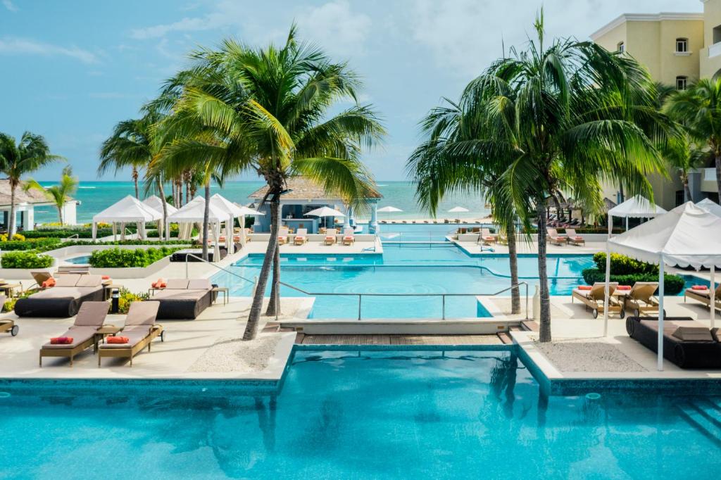 una piscina en el complejo con palmeras y sillas en Iberostar Grand Rose Hall, en Montego Bay