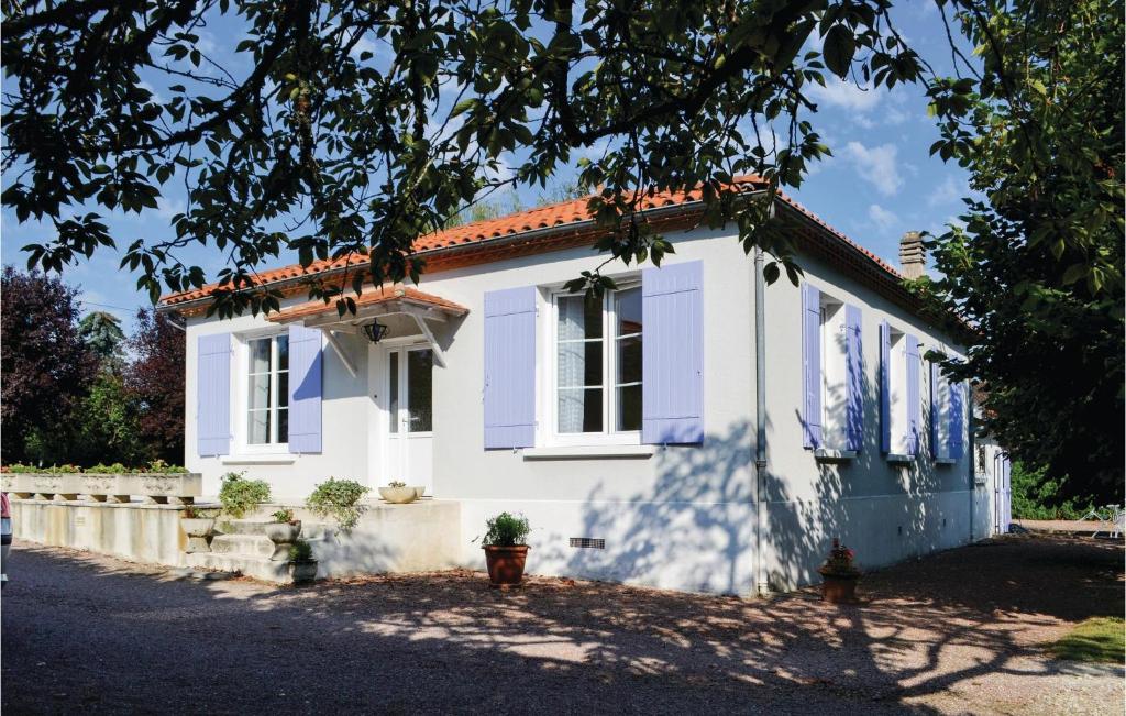 a white house with blue windows and a tree at Nice Home In Bassillac With Kitchen in Bassillac