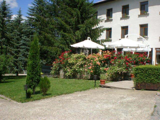 a garden with flowers and umbrellas in front of a building at Hotel Perfect in Yamna