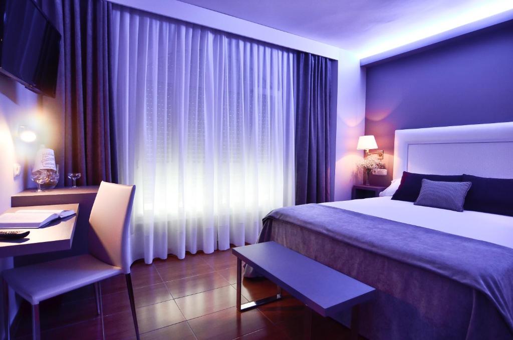 a hotel room with a bed and a desk and a bed and curtains at Hotel Jucamar in Cangas de Morrazo
