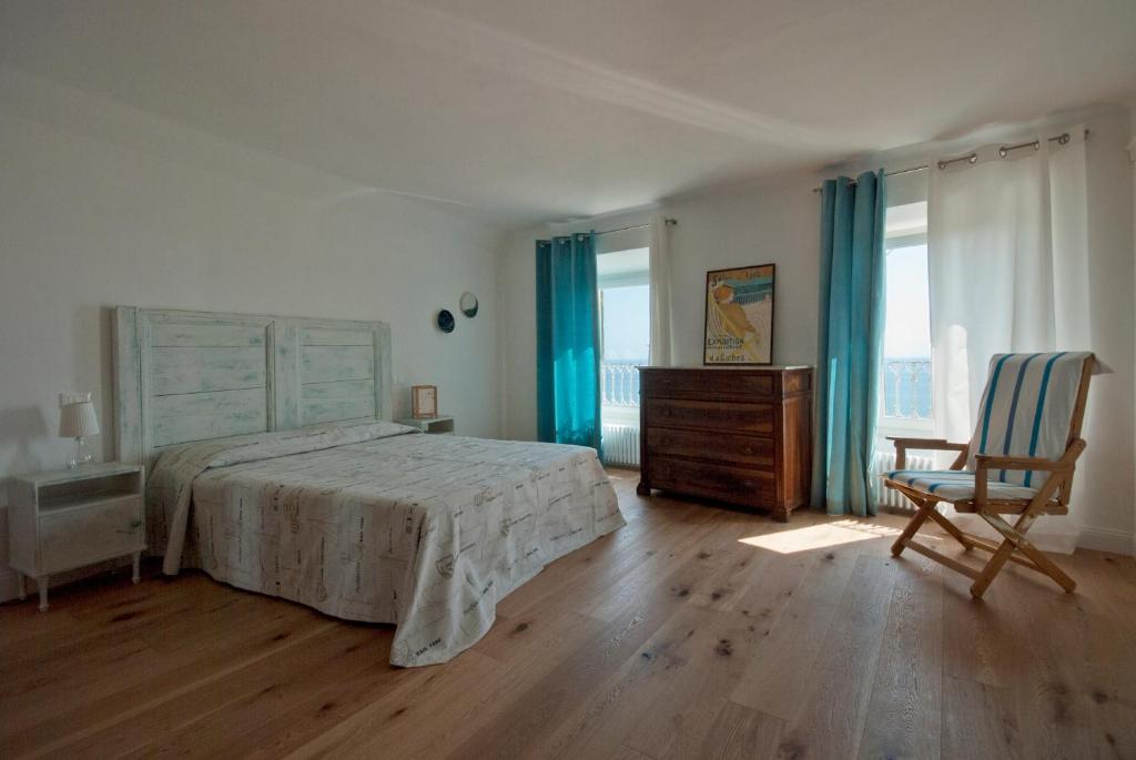 B&B Tre Finestre sul Mare في غْروتّامّاري: غرفة نوم بسرير وكرسي ونوافذ