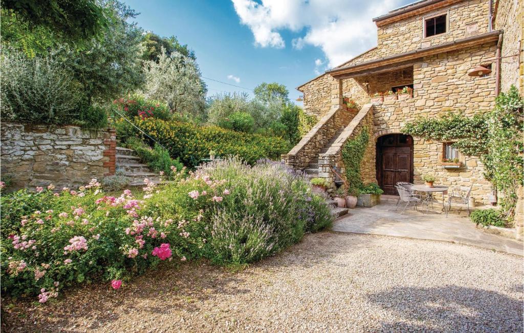 a garden with a stone house with a table and flowers at Casa Al Vento in Battifolle