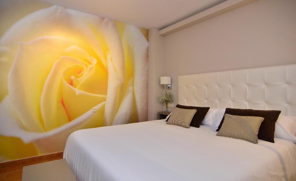 カンガス・デ・モラソにあるオテル フカマールの白いベッド1台、壁に花の絵が飾られたベッドルーム1室