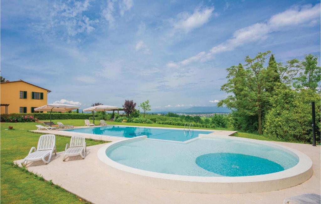 a large swimming pool with two chairs and a house at Lavanda in Cerreto Guidi
