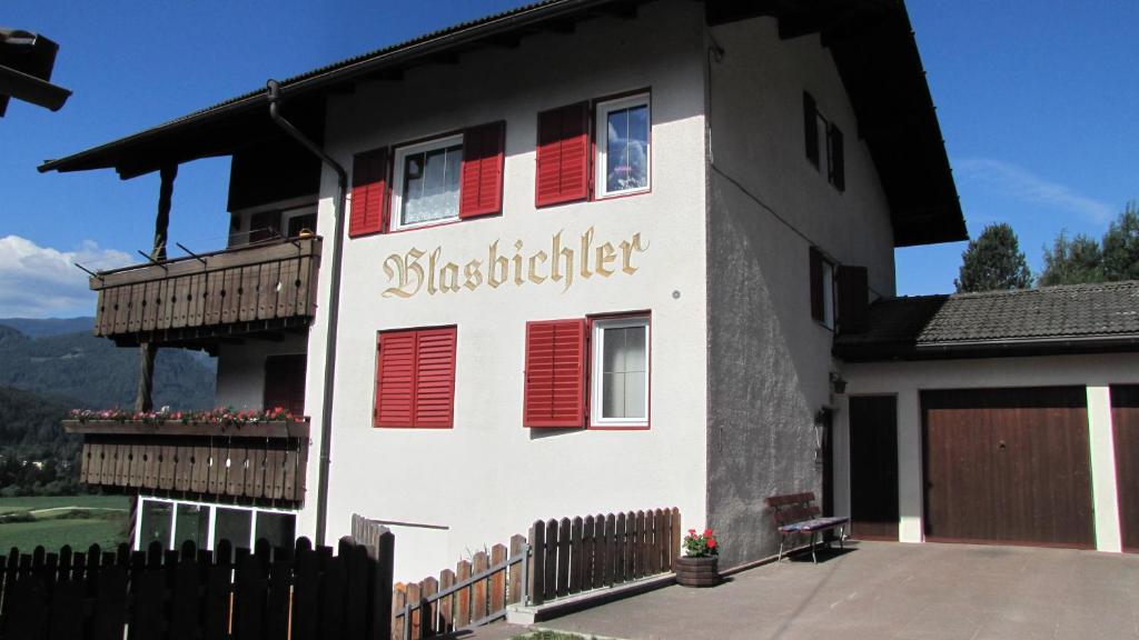 Casa blanca con persianas rojas y valla en Blasbichler Appartments, en Brunico