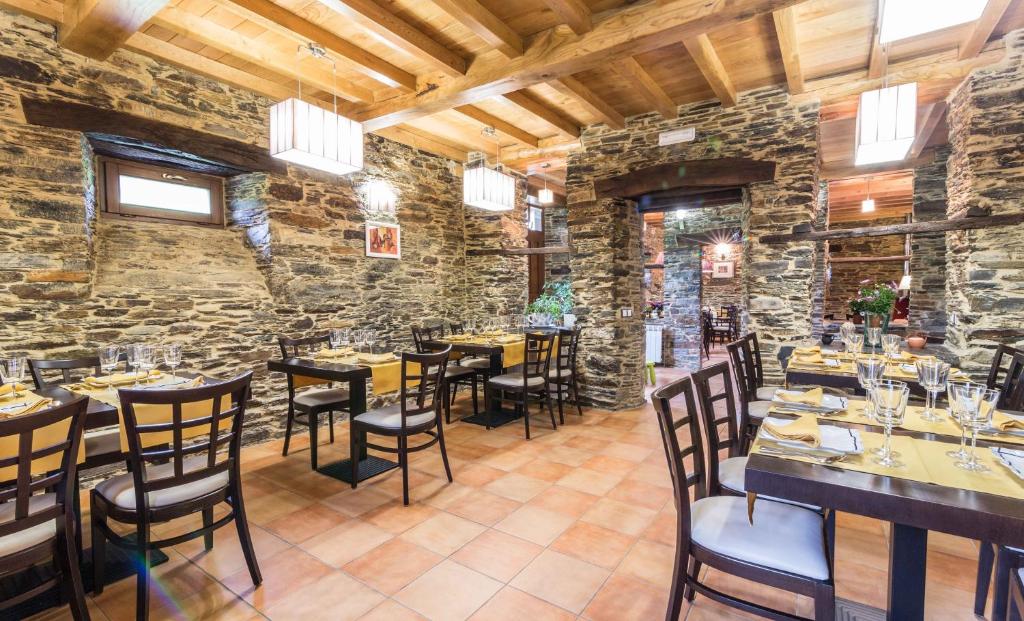 restauracja ze stołami i krzesłami w kamiennej ścianie w obiekcie Finca O Bizarro w mieście Trabada