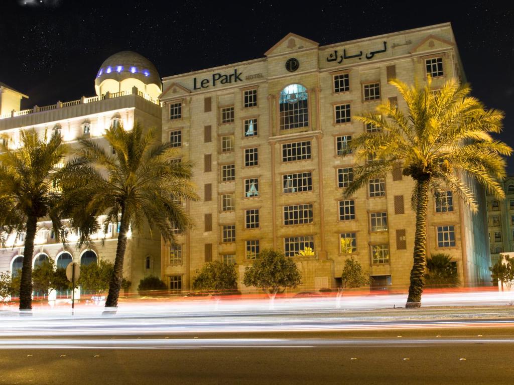 een groot gebouw met palmbomen voor een straat bij Le Park Hotel in Doha