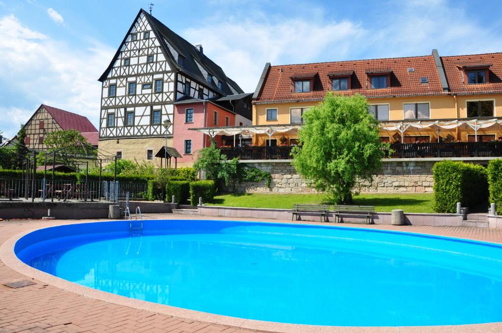 une grande piscine bleue en face d'un bâtiment dans l'établissement Landhotel Edelhof, à Uhlstädt