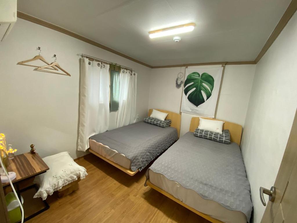 a bedroom with two beds and a desk and a table at Saesori Guesthouse in Gangneung