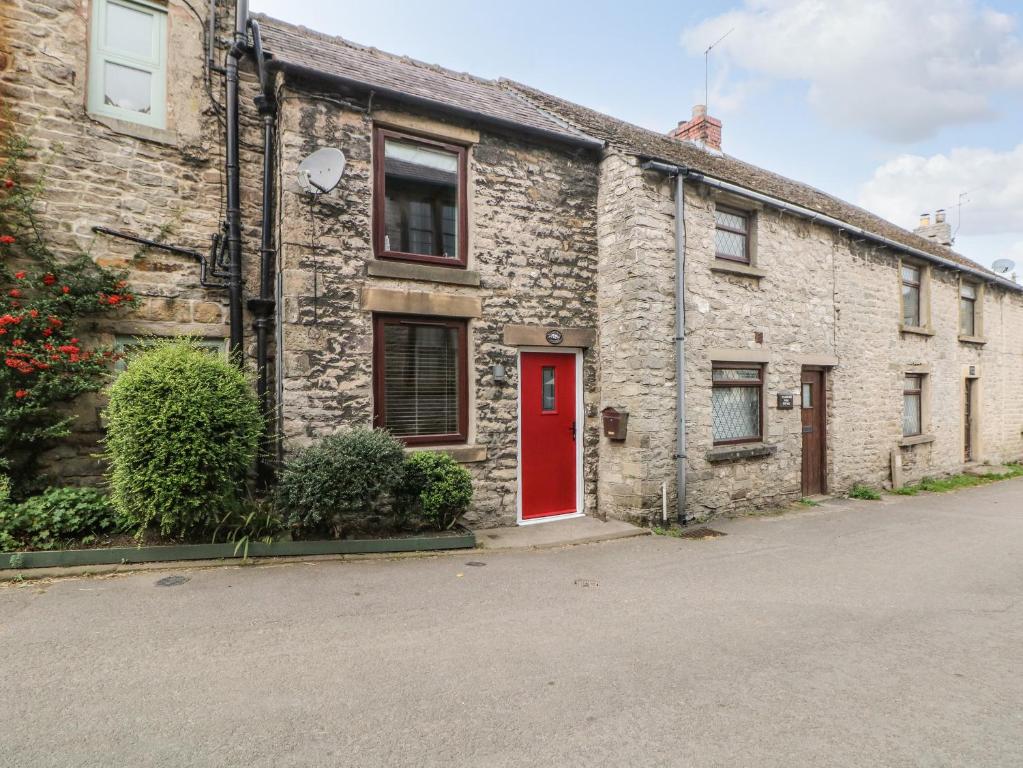 a brick house with a red door on a street at Mill Bridge Cottage in Castleton