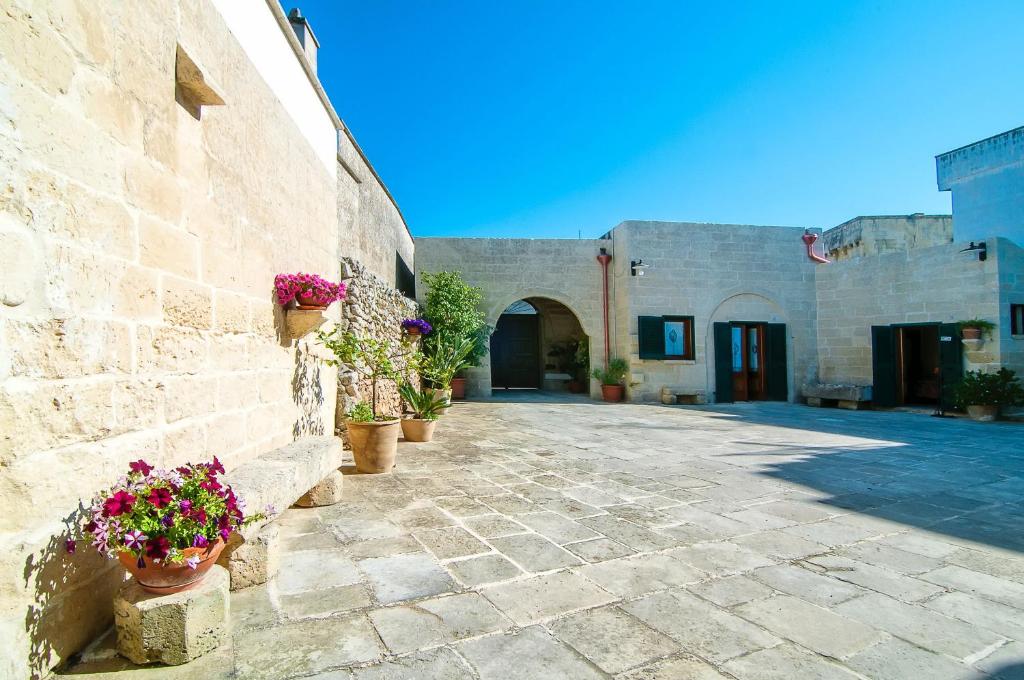 a stone courtyard with potted plants and a building at Antica Corte B&B in Acquarica
