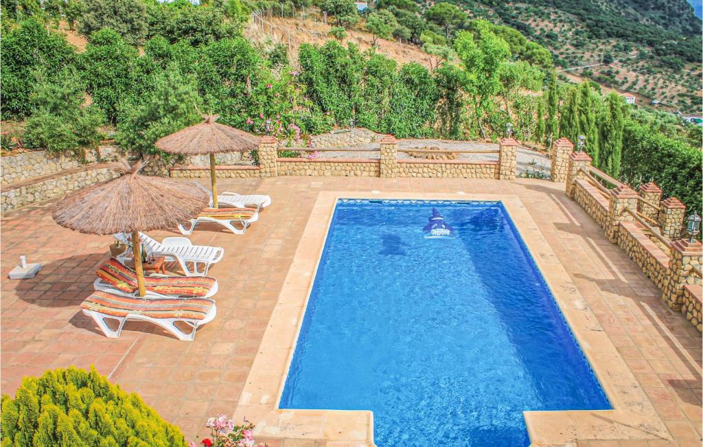 艾加斯托的住宿－Stunning Home In El Gastor With Wifi，一个带遮阳伞和椅子的室外游泳池和一个游泳池