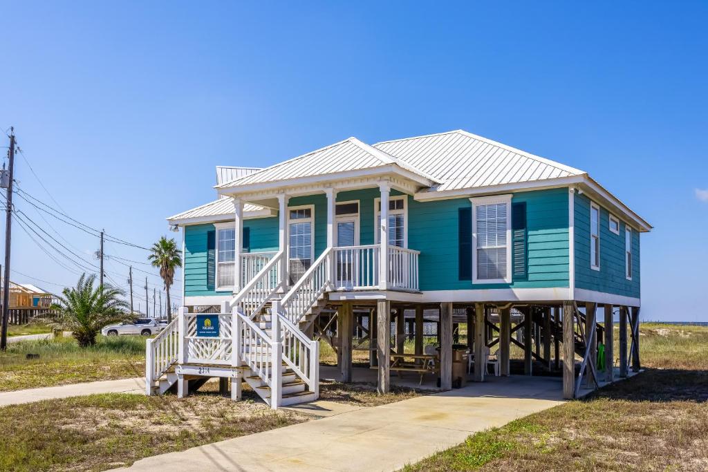 ドーフィン・アイランドにあるMalibu Beach House IIの白いポーチと階段のある青い家