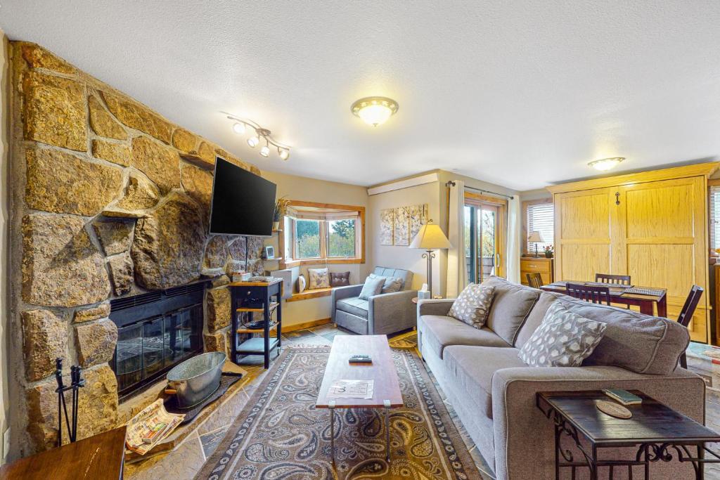 a living room with a couch and a stone fireplace at Winter Park River Studio in Winter Park