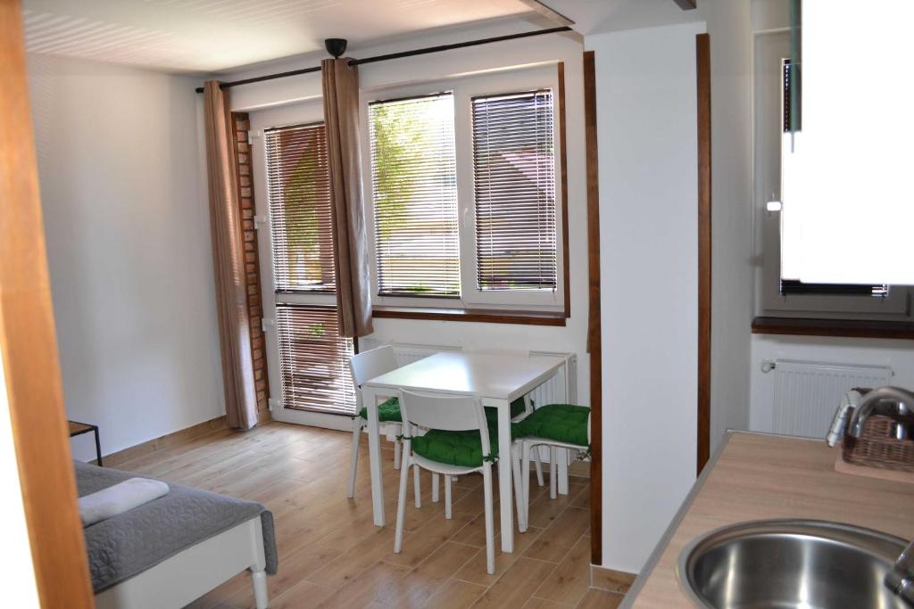 - une cuisine avec une table et des chaises blanches dans l'établissement Pitypang Apartman Felsőtárkány, à Felsőtárkány