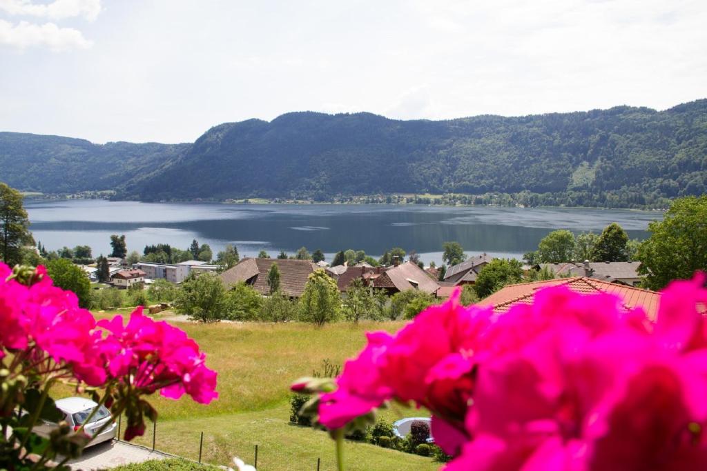 een uitzicht op een meer vanaf een veld met roze bloemen bij FEWO Wonta am Ossiachersee in Sattendorf