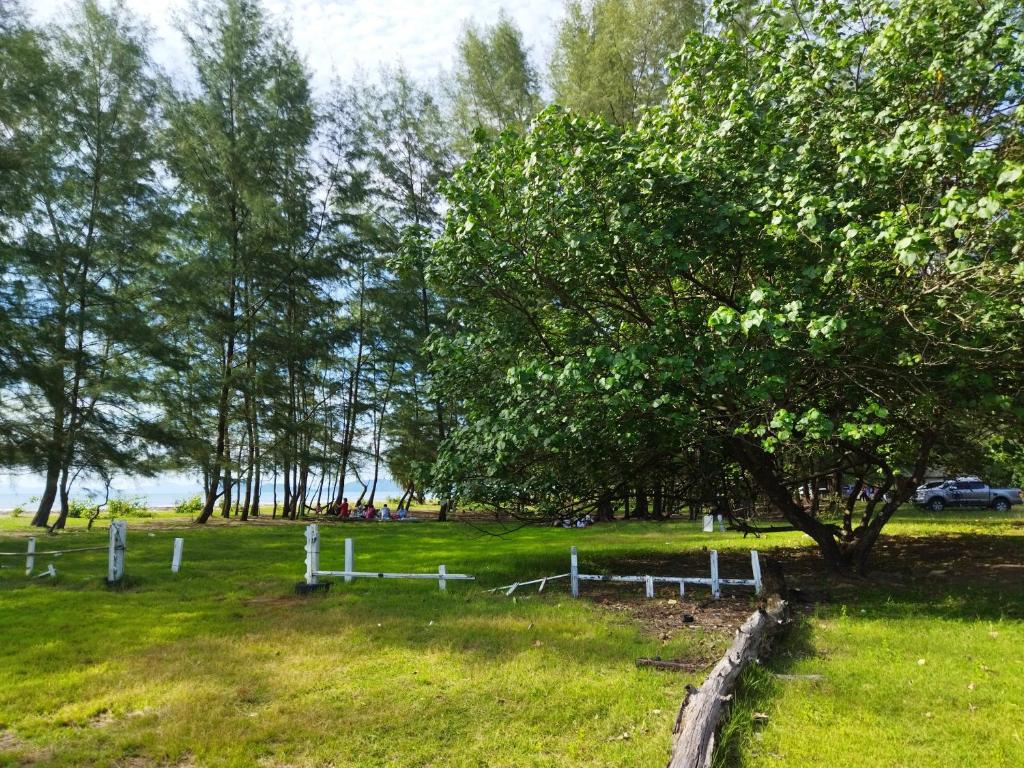een veld met een boom en een wit hek bij Andaman Peace Resort in Ranong