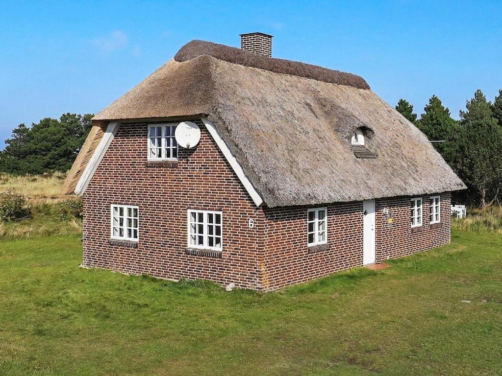 una antigua casa de ladrillo con techo de paja en un campo en 7 person holiday home in Bl vand, en Blåvand