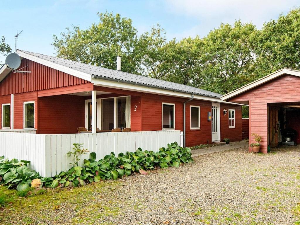 a red house with a white fence in front of it at 6 person holiday home in Hemmet in Hemmet