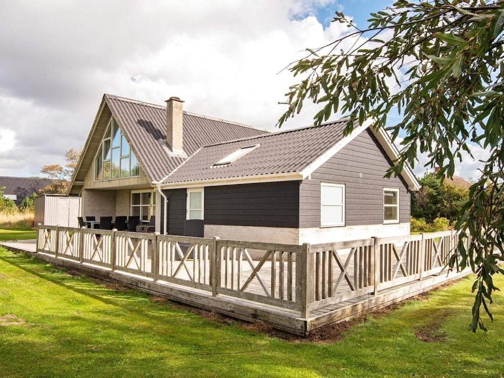 a house with a wooden fence in front of it at 8 person holiday home in Ulfborg in Fjand Gårde