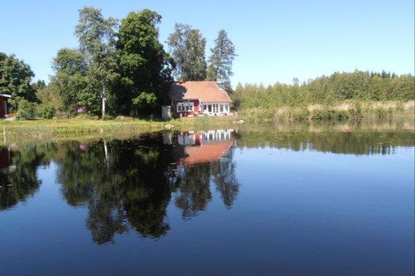 a house on the shore of a body of water at Lakeside VILLA in Nolmyra