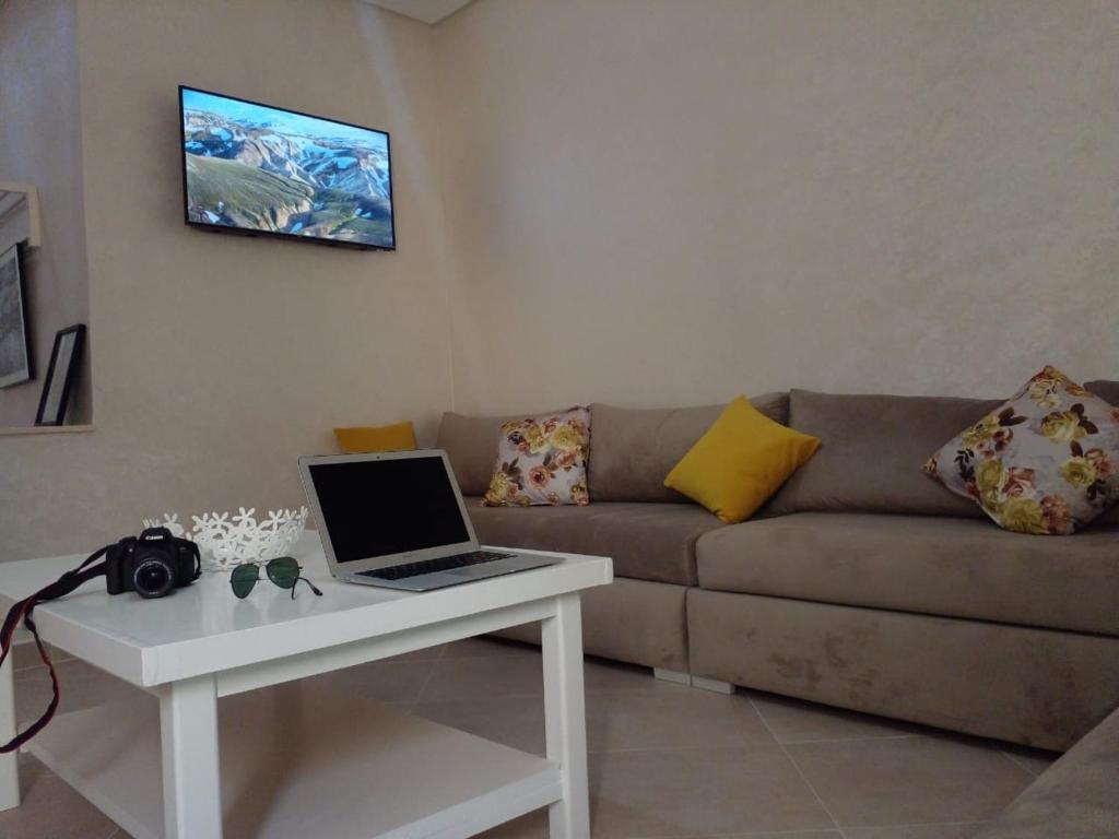 a living room with a couch and a laptop on a table at Panorama Apartment Nador Jadid Klima free Parking & Wifi in Nador