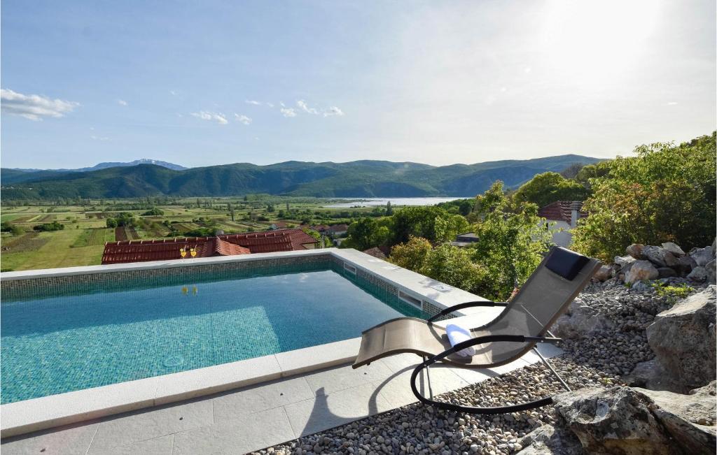 a swimming pool with a chair and a television at 2 Bedroom Awesome Home In Donji Prolozac in Juričići