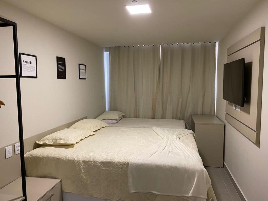 ein kleines Schlafzimmer mit einem Bett und einem TV in der Unterkunft Studio Vivendas do Mar in João Pessoa