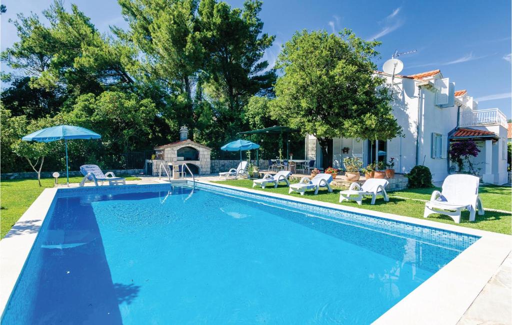 - une piscine avec des chaises et des parasols à côté d'une maison dans l'établissement Lovely Home In Mocici With Kitchen, à Čilipi