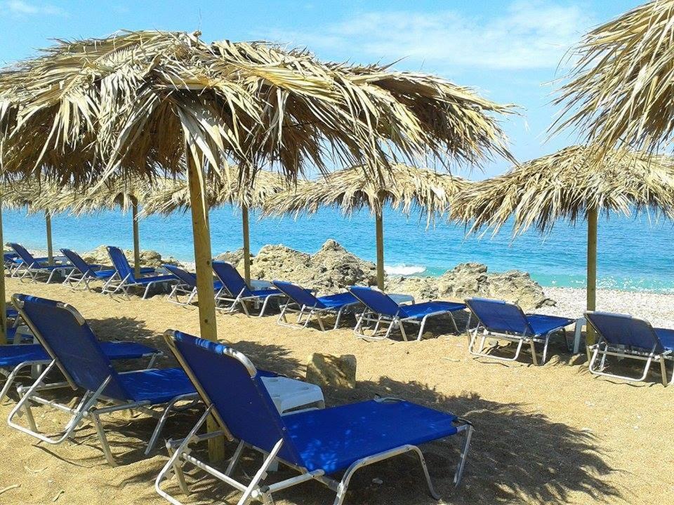 un grupo de sillas y sombrillas en una playa en Akrogiali, en Kyparissia